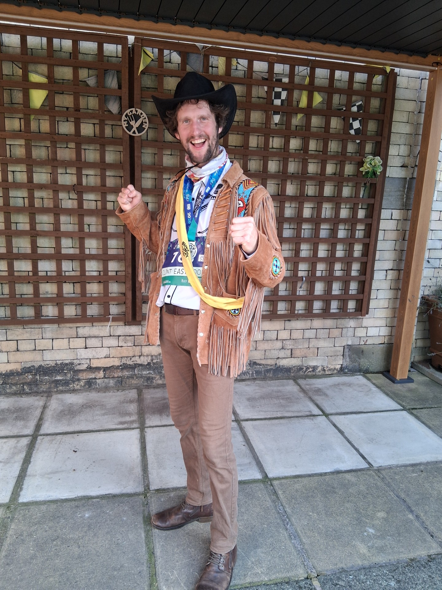 Michael: Michael smiles for the camera wearing a cowboy hat and full cowboy outfit after completing the Bury 10K.